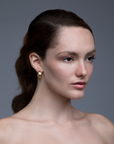 model wearing Gadir Earrings, gold earrings with flat and perforated plates
